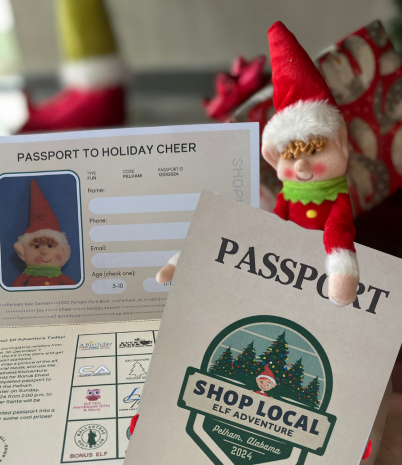 Pete the Pelham Elf holds the 2024 Elf Adventure Passport against a background of Christmas presents