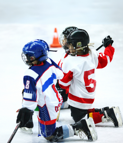 Young hockey players in gear and mask kneel on the ice